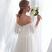 Woman in a white wedding dress holding flowers in a softly lit room.