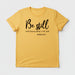 Yellow t-shirt with 'Be still and know that I am God' text, paired with jeans and sneakers on a wooden surface.