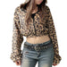 Person wearing a leopard print jacket and jeans against a plain background