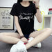 Person wearing a black t-shirt with white text sitting on the floor.