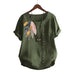 Green blouse with floral embroidery on a hanger against a beige wall