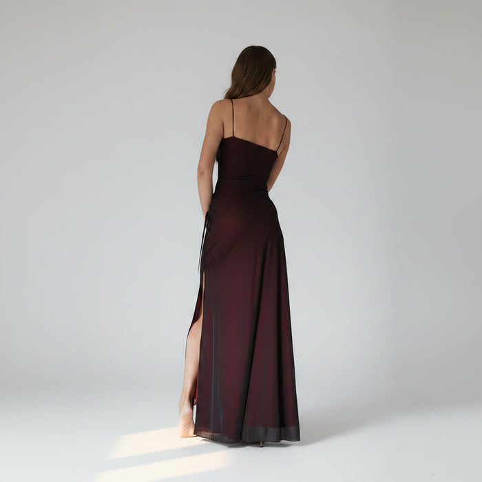 Long dark red evening gown with thin straps and a slit on a white background