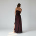 Long dark red evening gown with thin straps and a slit on a white background