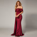 Woman in a burgundy off-shoulder gown standing against a dark background
