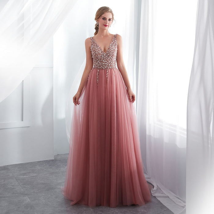 Woman wearing a pink evening gown with a beaded top in a bright room.