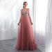 Woman wearing a pink evening gown with a beaded top in a bright room.